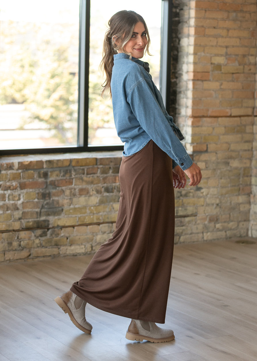 Flowy chocolate brown knit maxi skirt styled with a denim shirt and neutral ankle boots.