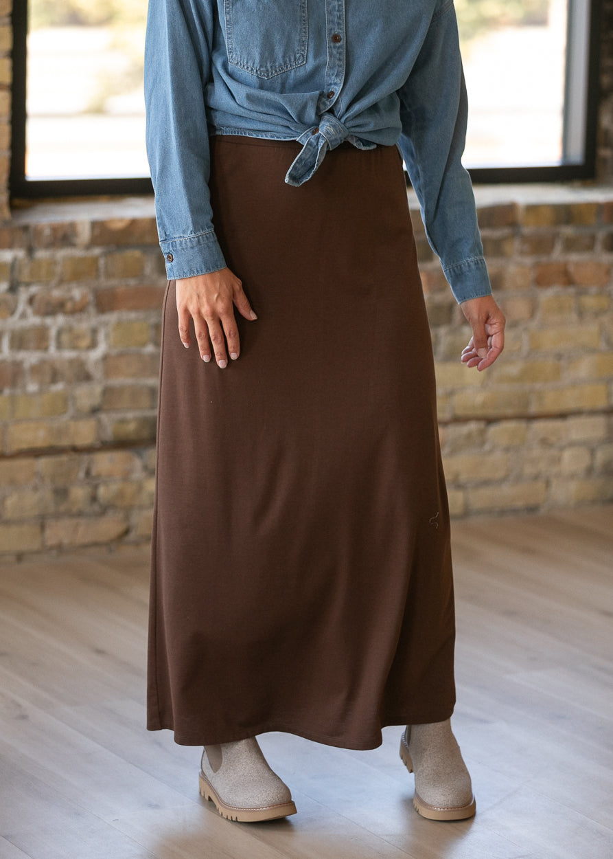 Chocolate brown knit maxi skirt with a wide waistband, styled with a knotted denim button-up.