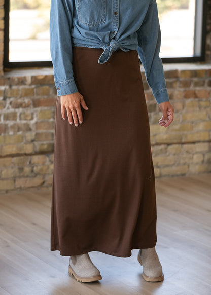 Chocolate brown knit maxi skirt with a wide waistband, styled with a knotted denim button-up.