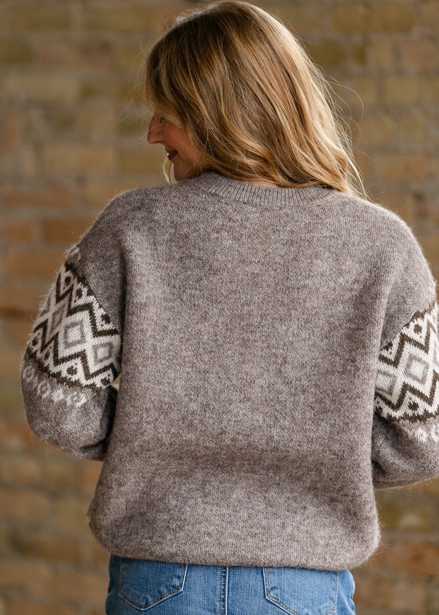 Close-up of taupe, cream, and brown geometric knit pattern across the sweater front.