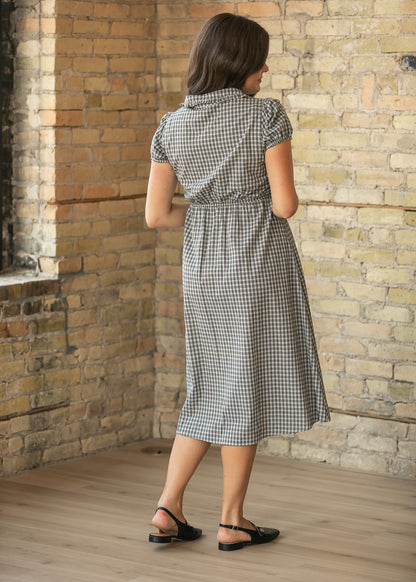 Back of dark navy gingham midi dress showing gathered waist, short puff sleeves, and below-knee hem.