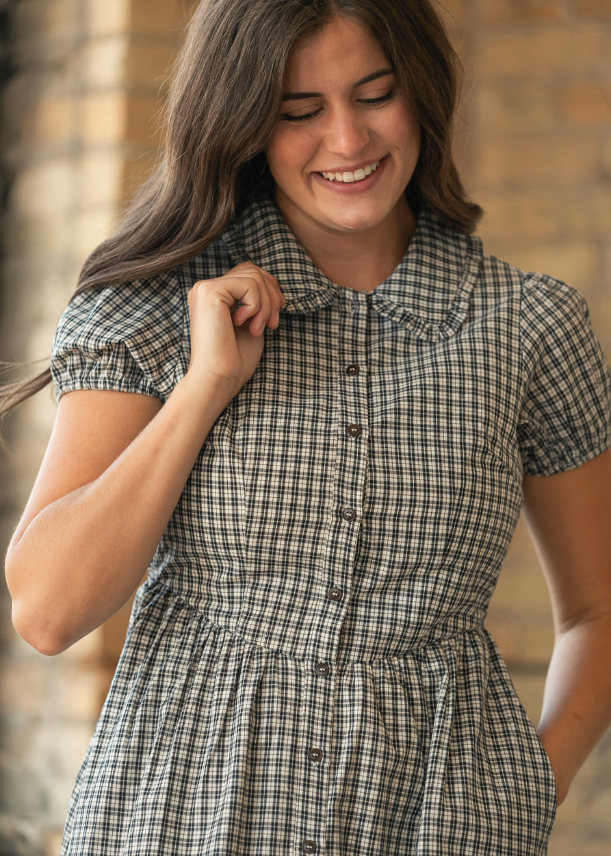 Close-up of gingham midi dress with ruffled collar, puff sleeves, fitted bodice, and gathered waist.