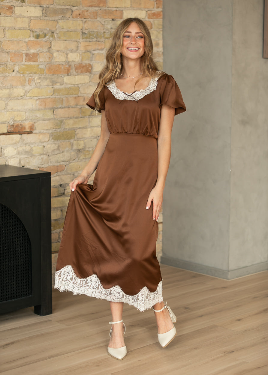 Front view of chocolate brown lace trim midi dress with flutter sleeves and scalloped cream lace hem.
