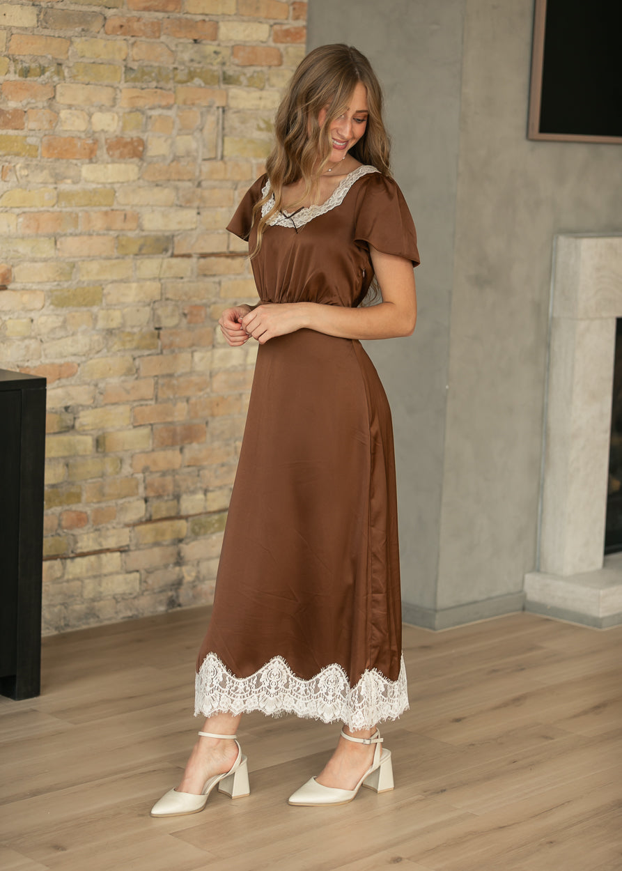 Chocolate brown midi dress with cream lace neckline and hem, shown with a flowing semi-fitted silhouette.