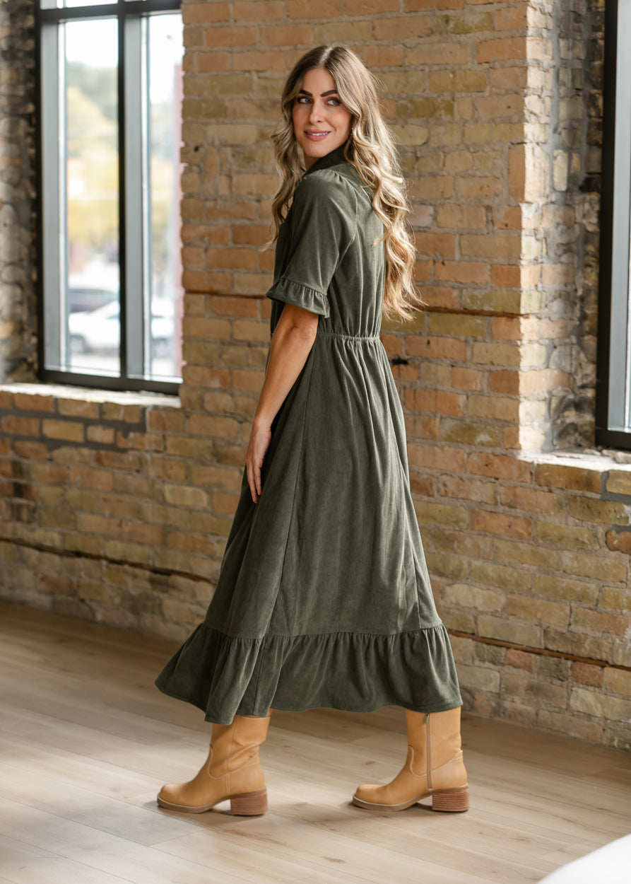 Side view of olive corduroy midi dress showing the semi-fitted waist and flowing midi skirt.