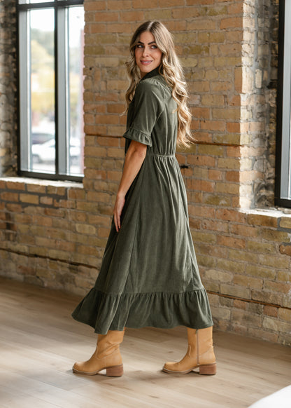 Side view of olive corduroy midi dress showing the semi-fitted waist and flowing midi skirt.
