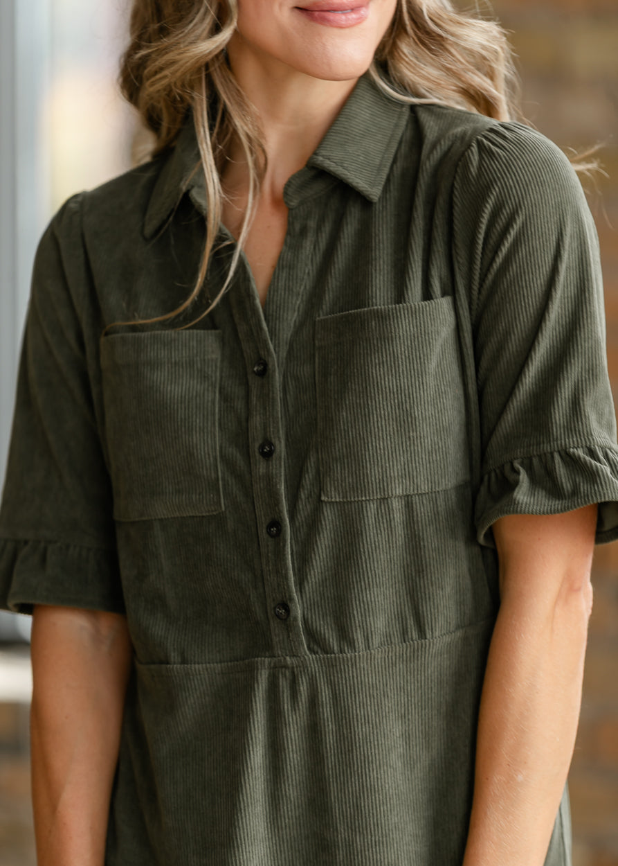 Close-up of olive corduroy midi dress showing the collar, functional buttons, chest pockets, and ruffle sleeves.