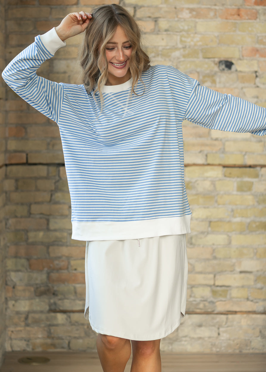Relaxed cornflower blue mini striped crewneck sweater showing roomy fit and hip-length hem.