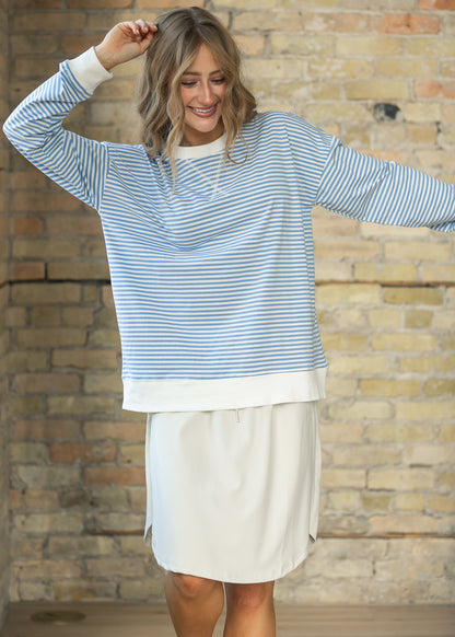 Relaxed cornflower blue mini striped crewneck sweater showing roomy fit and hip-length hem.