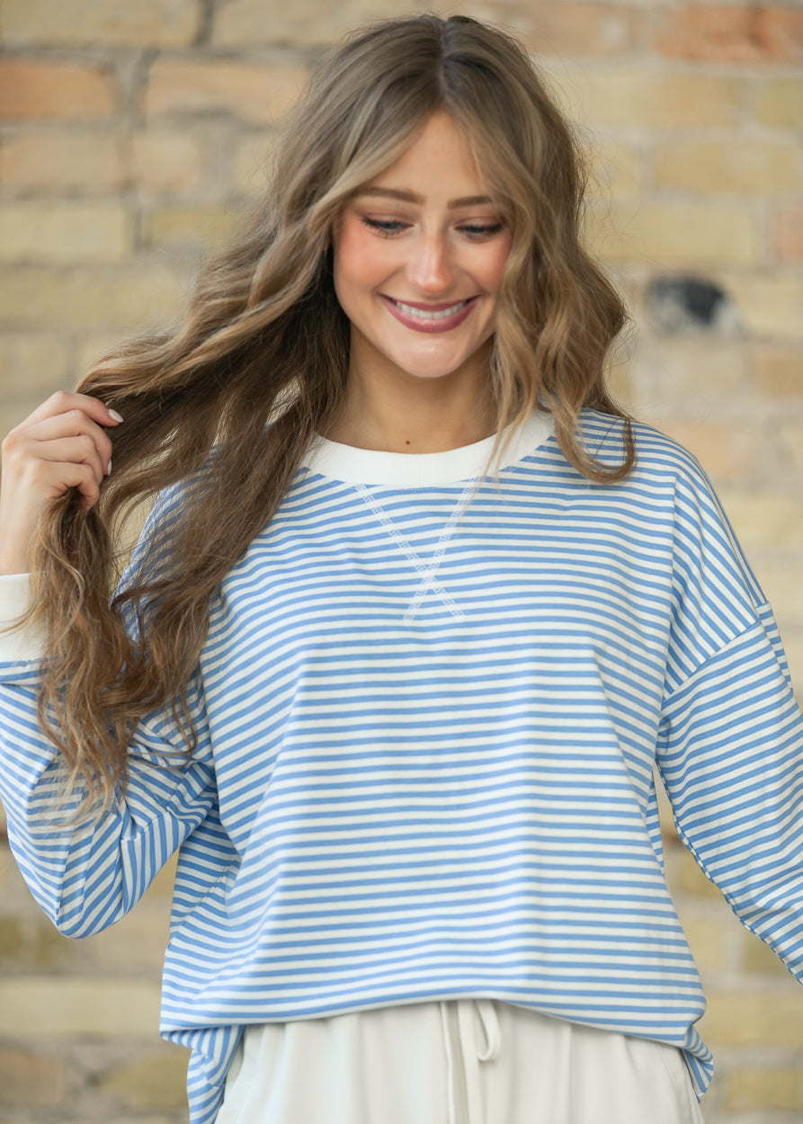 Close-up of mini striped crewneck sweater showing white neckline and decorative center stitching.