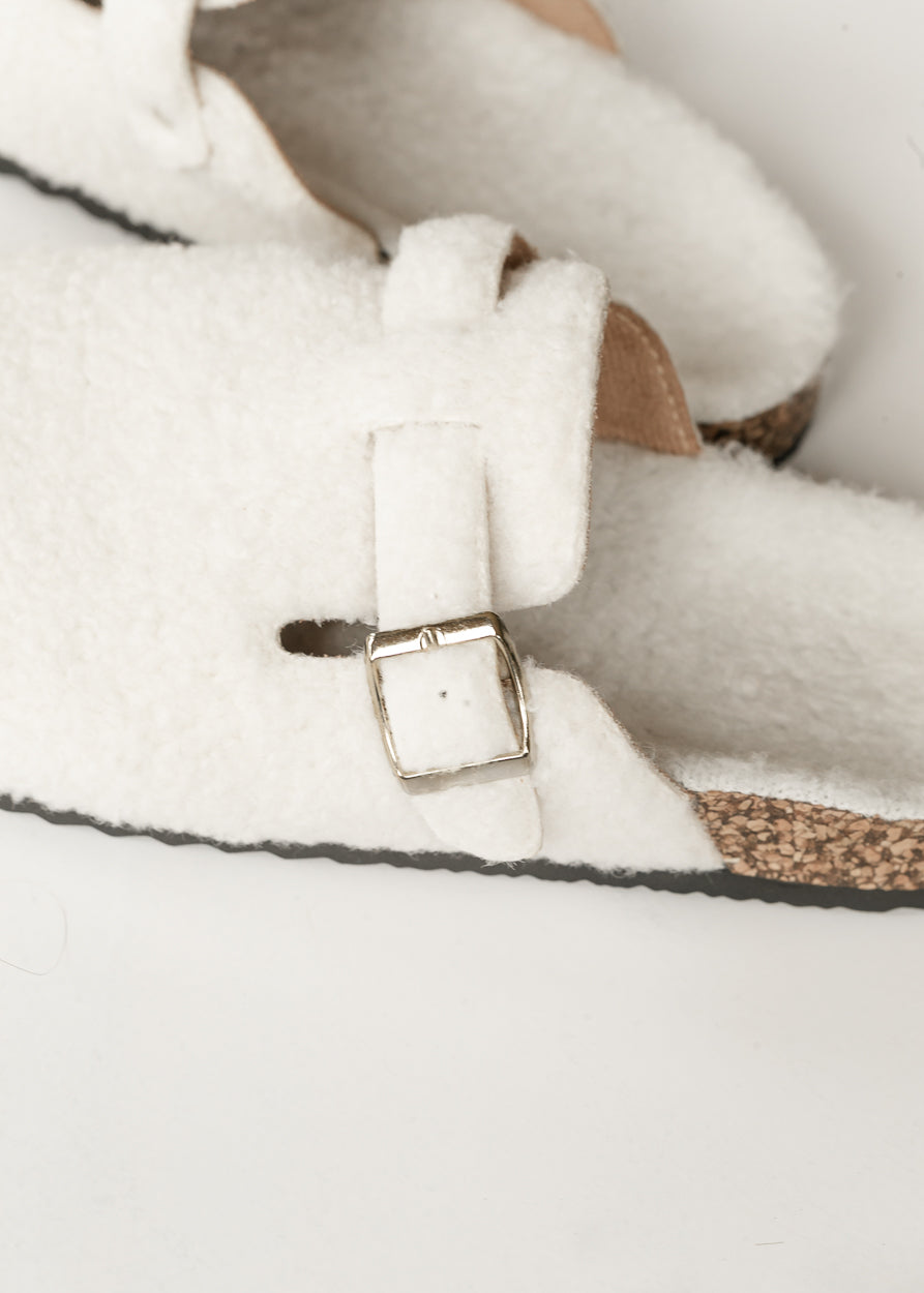 Ivory sherpa clogs styled with a denim skirt, shown on foot outdoors.