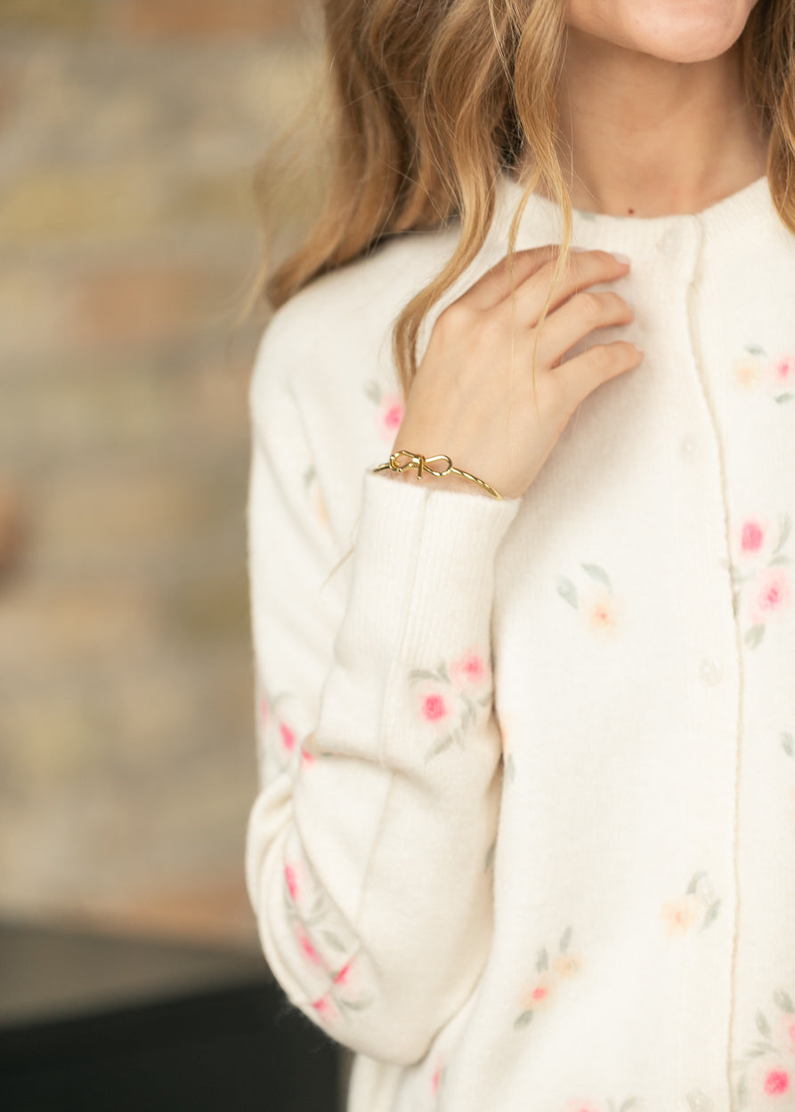 Close-up of a cream floral long sleeve knit cardigan showing the floral print and front button detail