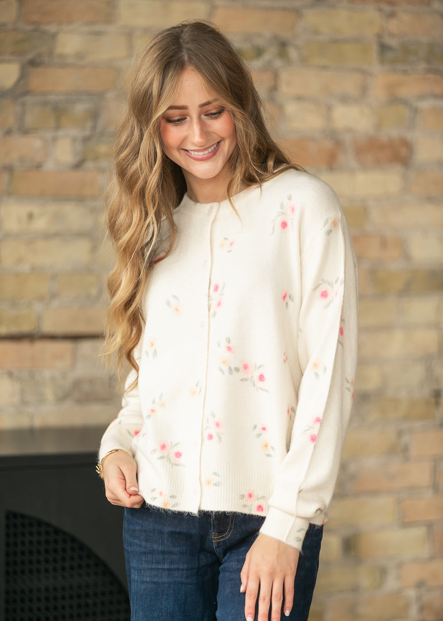 Angled front view of a cream floral long sleeve knit cardigan with a soft floral print