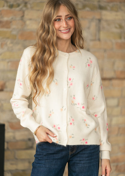 Front view of a model wearing a cream floral long sleeve knit cardigan with functional buttons