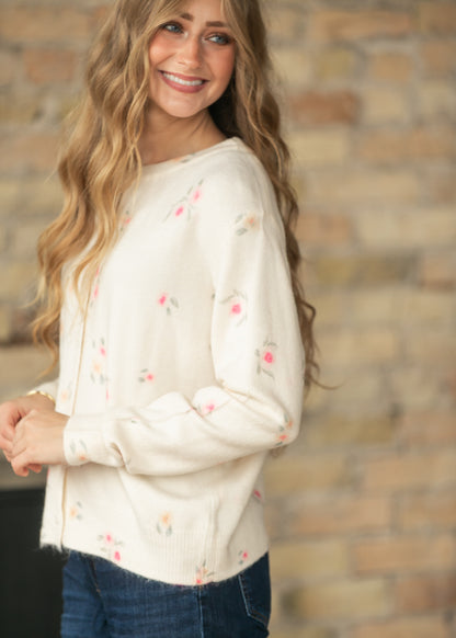 Side view of a cream floral long sleeve knit cardigan styled with dark wash jeans