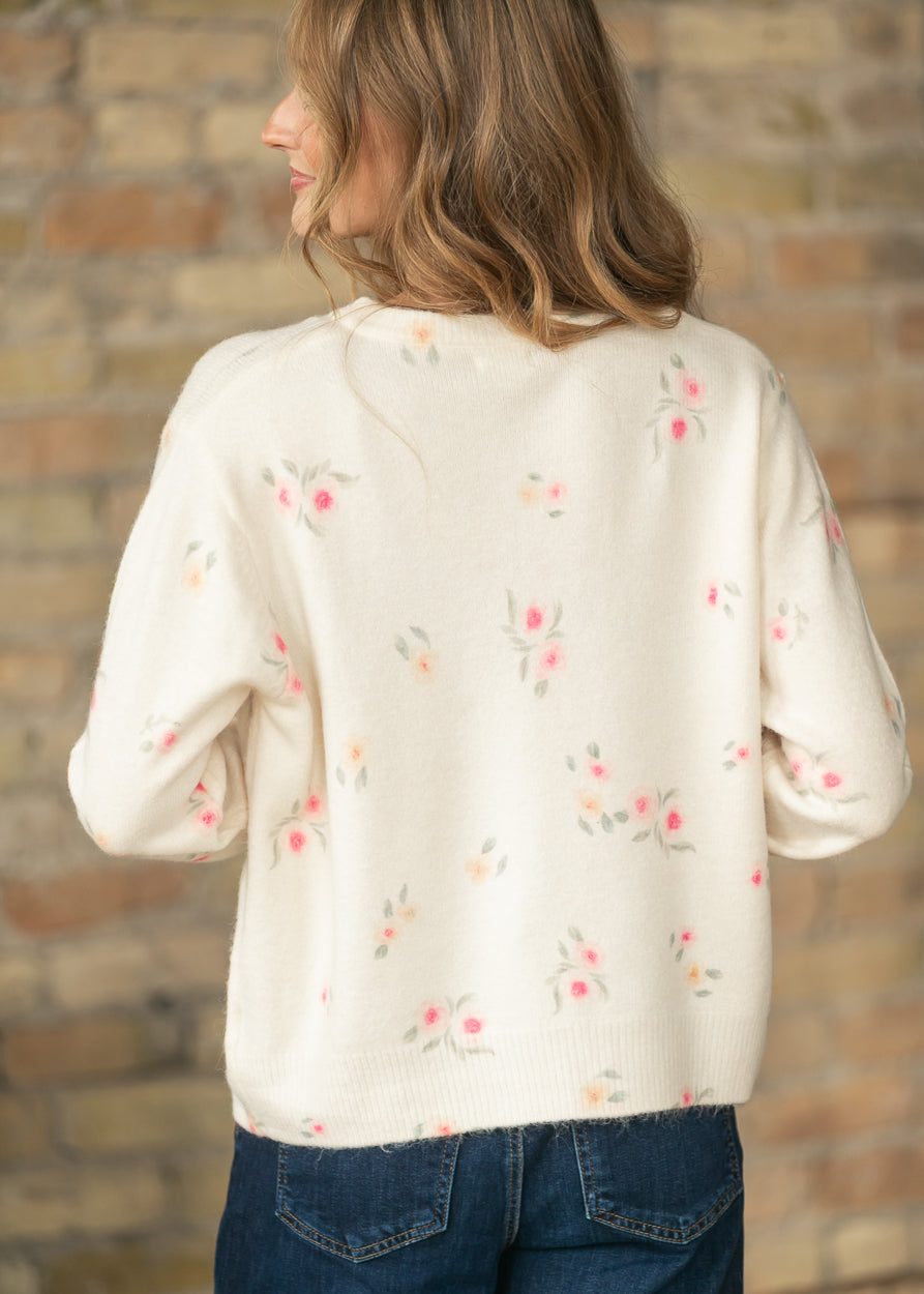 Back angled view of a cream floral long sleeve knit cardigan with scattered pink and peach flowers
