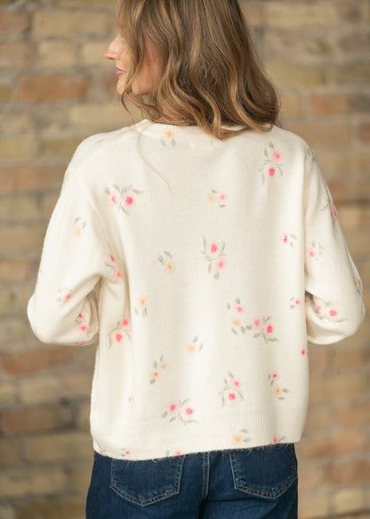 Back angled view of a cream floral long sleeve knit cardigan with scattered pink and peach flowers