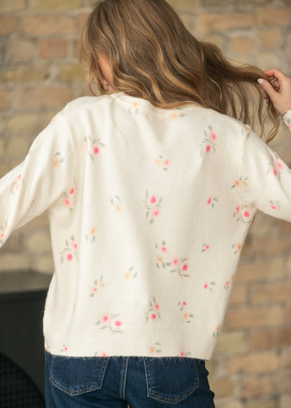Back view of a cream floral long sleeve knit cardigan paired with dark wash jeans