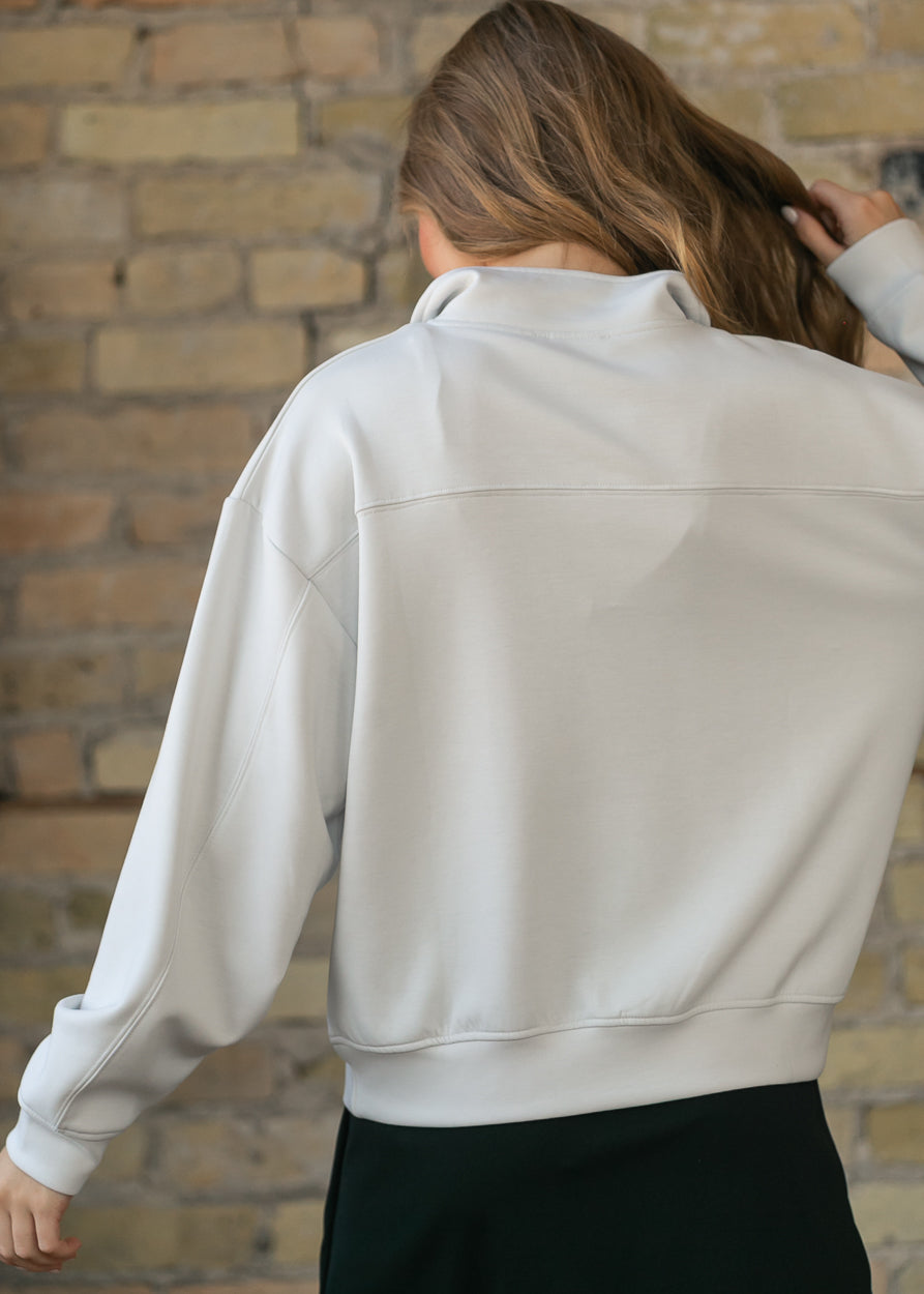 Back of cream quarter-zip sweatshirt showing the yoke seam and funnel mock neck.