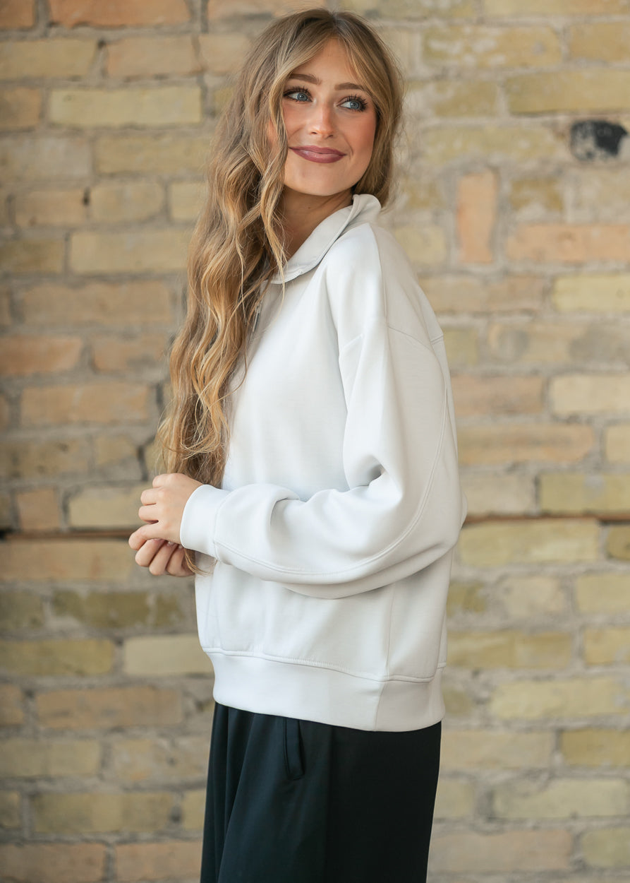 Side view of cream quarter-zip mock neck sweatshirt with dropped shoulder seams.