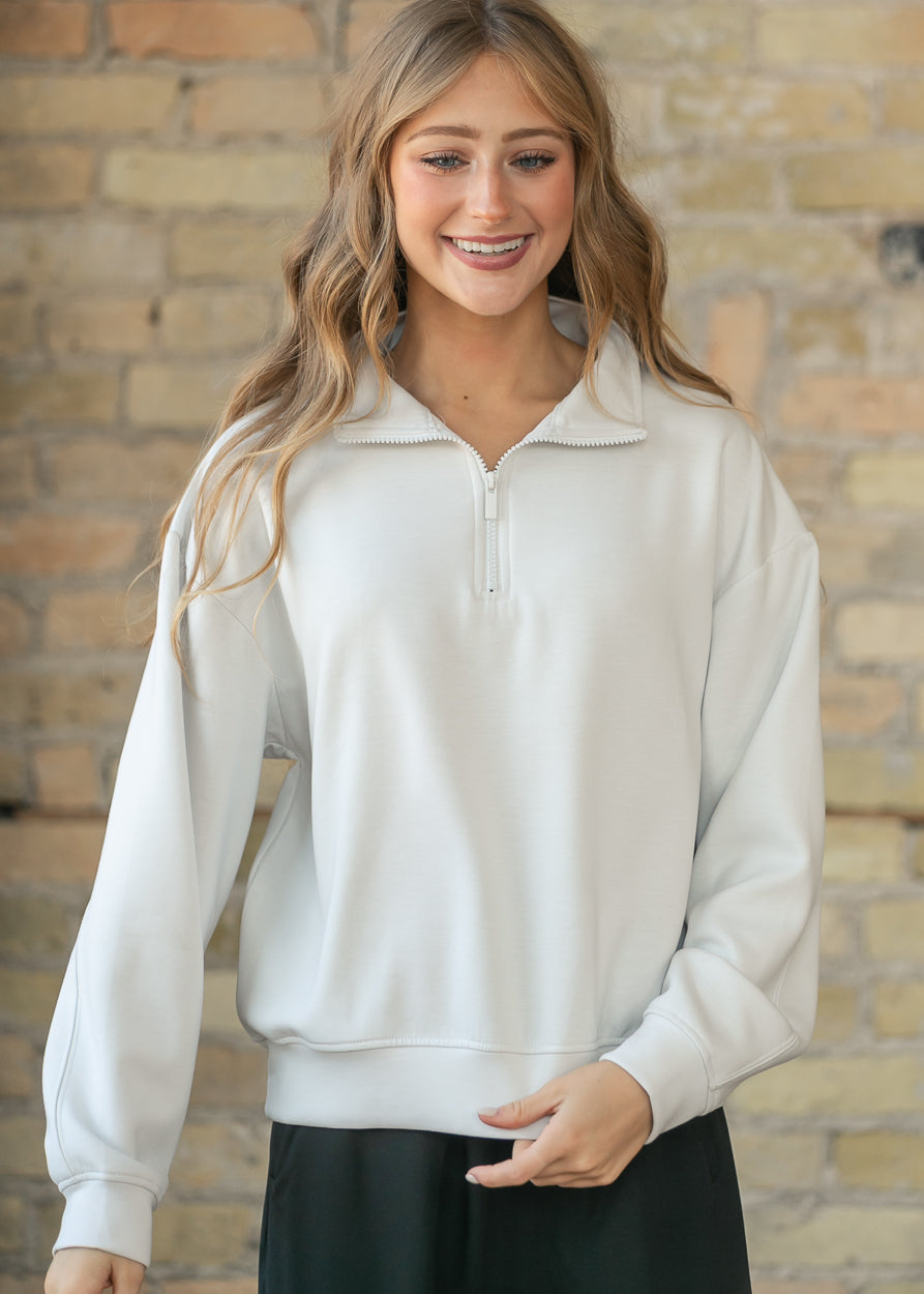 Cream quarter-zip mock neck sweatshirt with ribbed cuffs, zipped high for a cozy layered look.