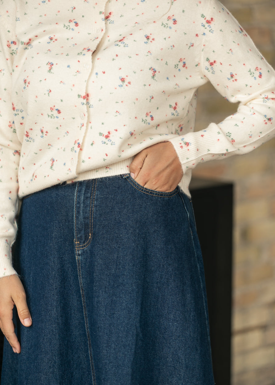 Close-up of dark wash denim midi skirt showing front pocket, contrast stitching, and A-line shape.