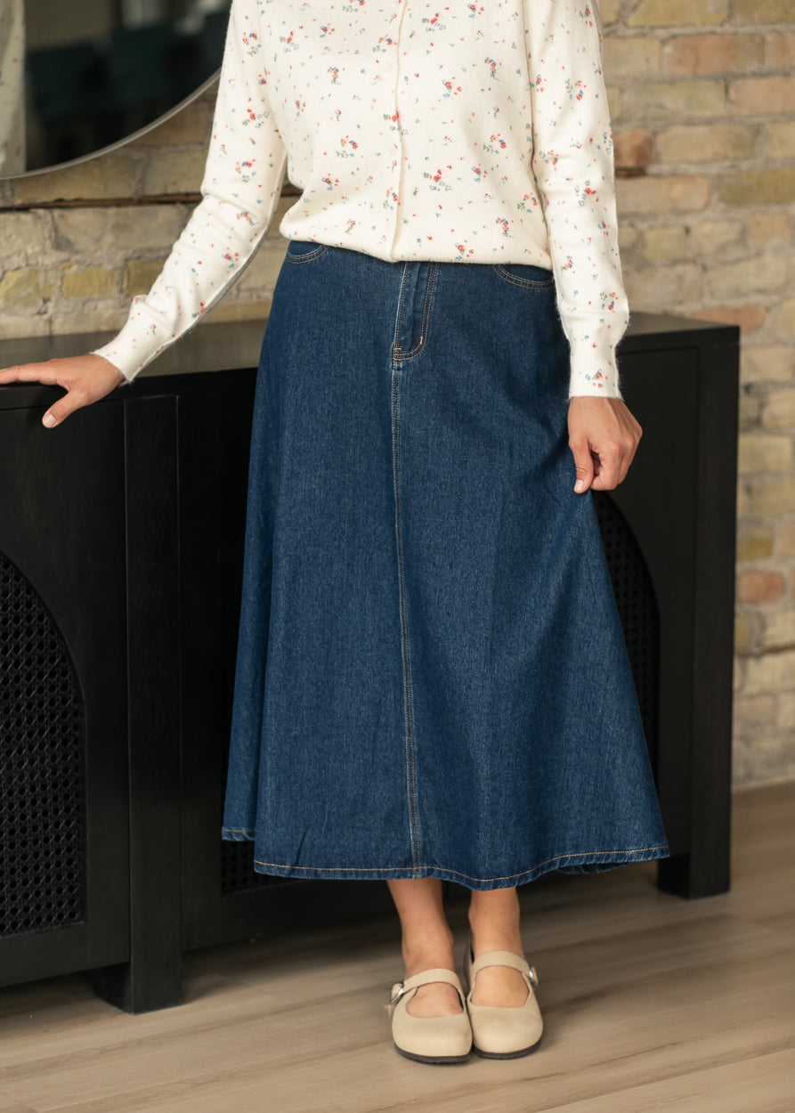 Dark wash denim midi skirt with softly flared A-line silhouette and front seam detail.