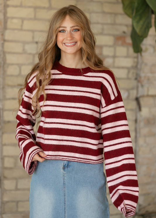 Burgundy striped sweater with a loose silhouette and long sleeves, paired with a light wash denim maxi skirt.