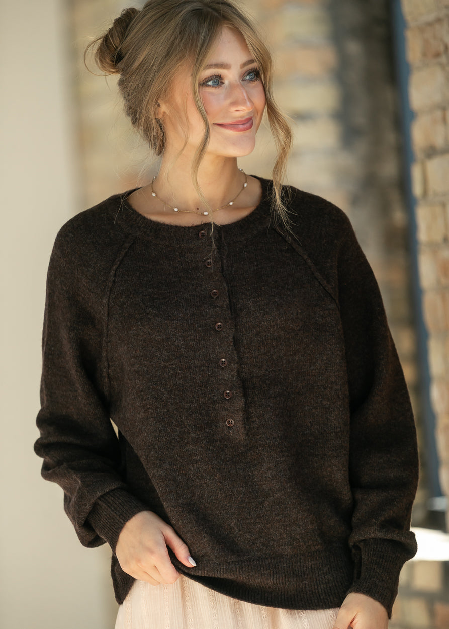 Close-up of the dark brown henley sweater's button placket and crew neckline.