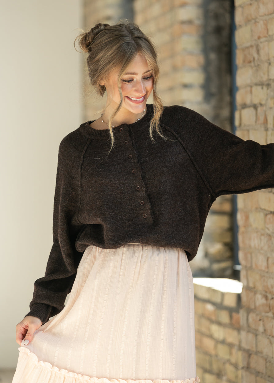 Close-up of the dark brown henley sweater's button placket and crew neckline.