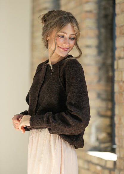 Dark brown henley sweater with a round neckline and button placket, side profile.