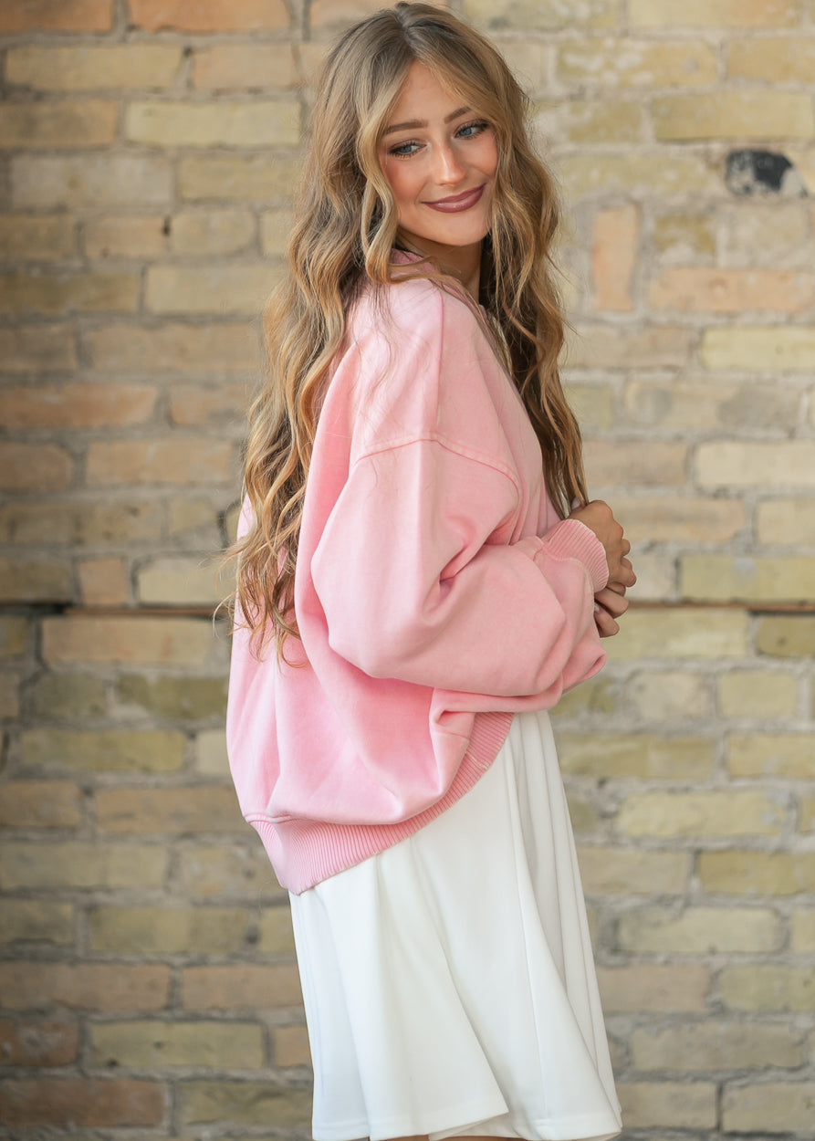 Side view of an oversized pink crewneck sweatshirt paired with a white midi skirt.