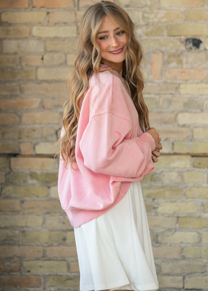 Side view of an oversized pink crewneck sweatshirt paired with a white midi skirt.