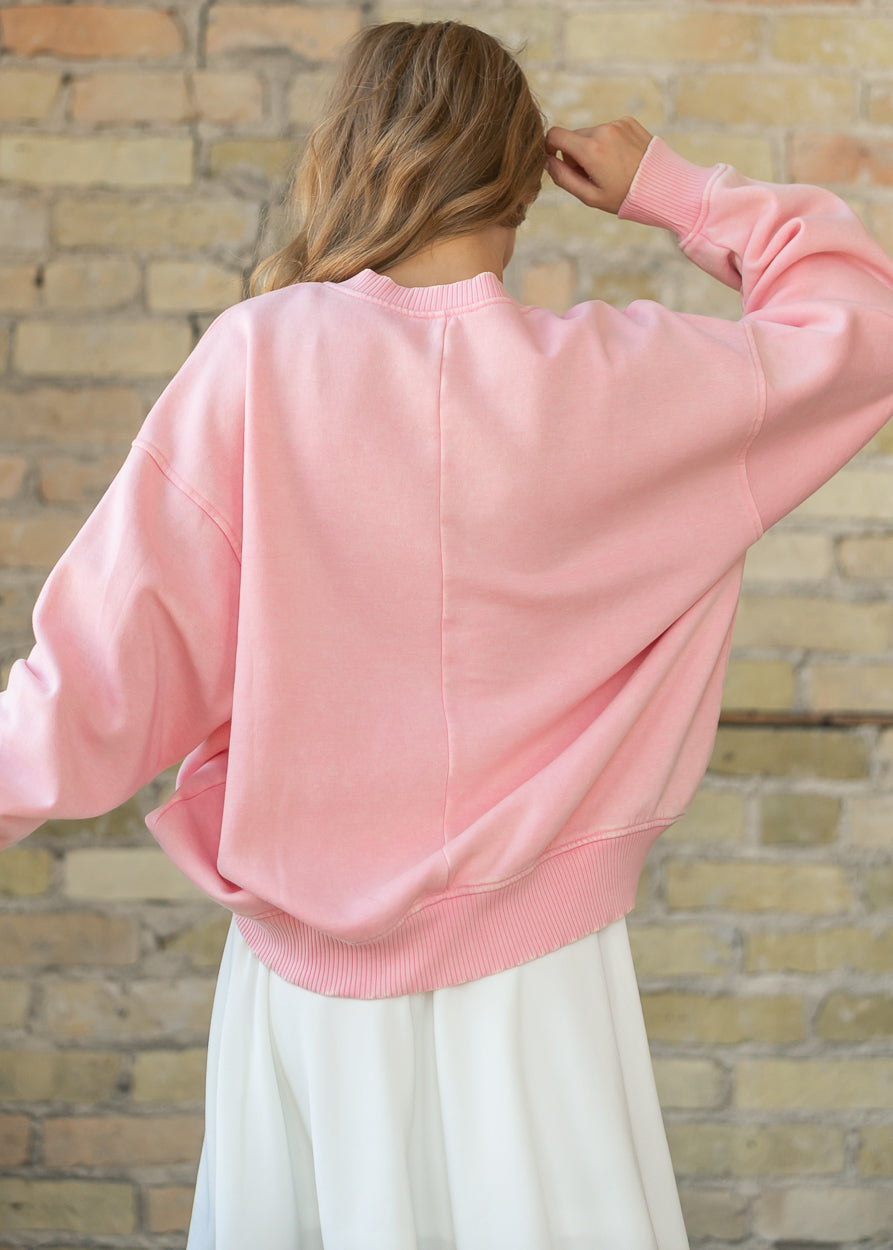 Close-up back view of a pink fleece sweatshirt with ribbed collar and cuff detail.