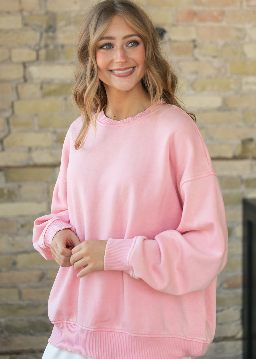 Oversized dusty pink fleece sweatshirt with dropped shoulders, styled with a white skirt.