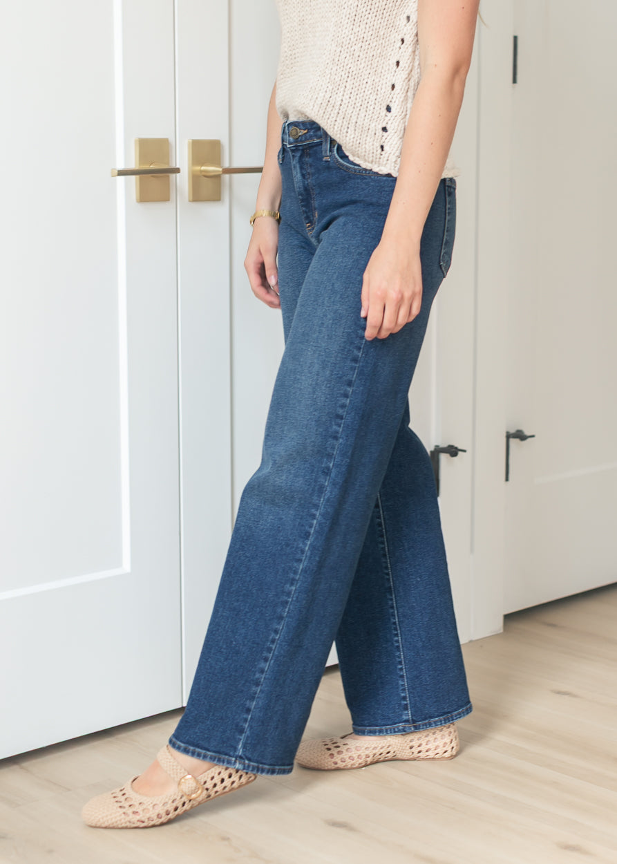 Side view of dark wash wide leg jeans showing full-length silhouette and subtle fading.