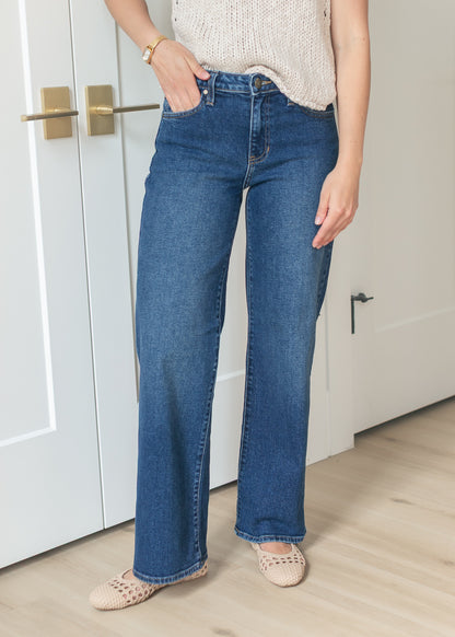 Front view of dark wash denim jeans with wide leg silhouette and classic five-pocket styling.