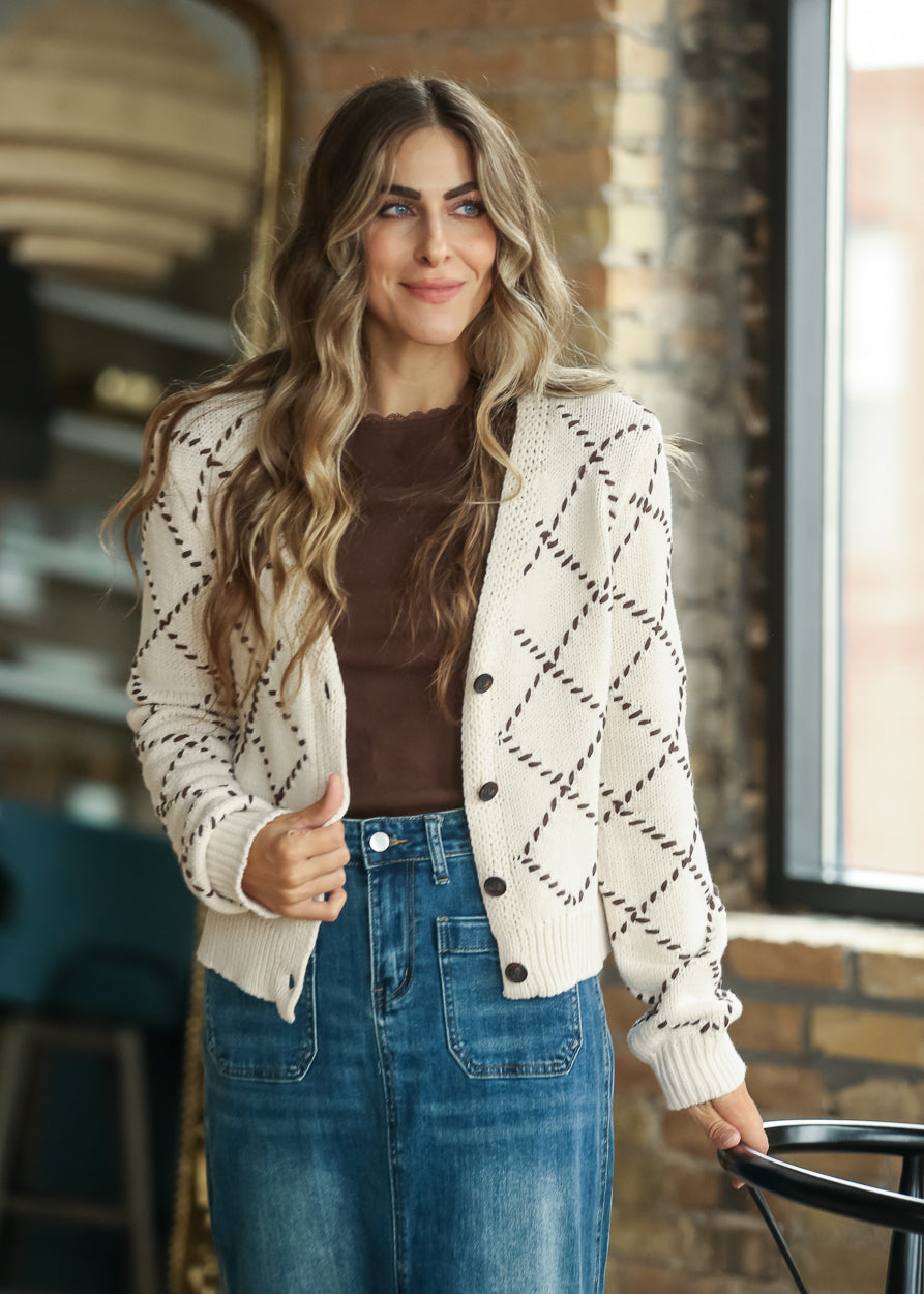 Cream button-front cardigan layered over a brown top with a long denim skirt.