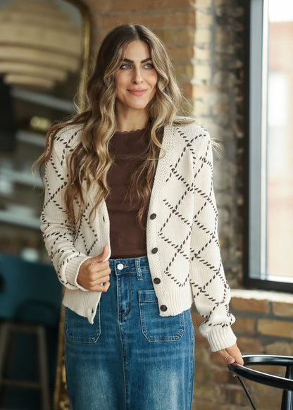 Cream button-front cardigan layered over a brown top with a long denim skirt.