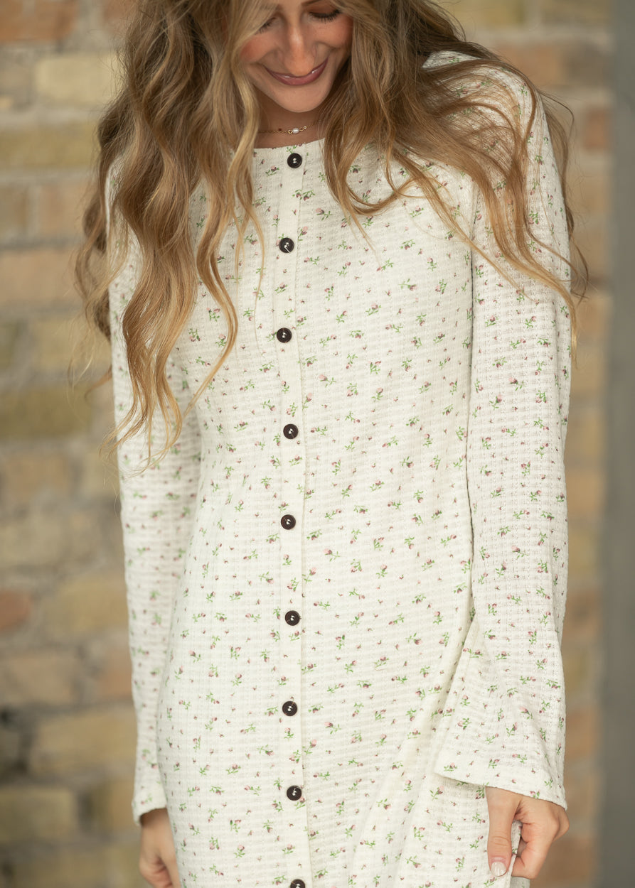 Close-up of cream floral maxi dress showing round neckline, dark buttons, and tiny pink floral print.