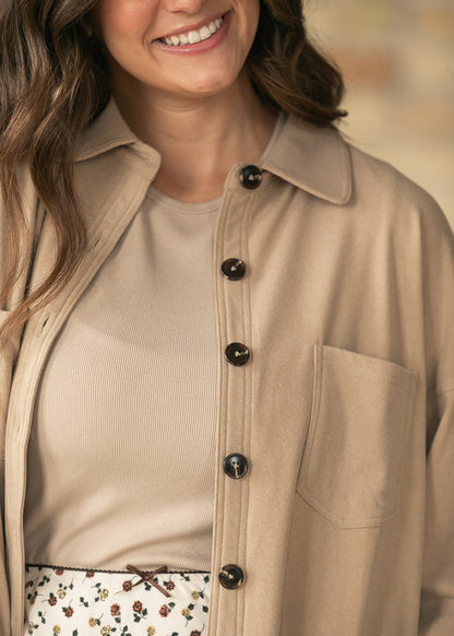 Close-up of taupe collared cardigan showing dark buttons, chest patch pocket, and soft fabric texture.