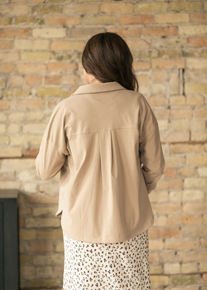 Back of warm taupe collared cardigan showing loose fit, back pleat detail, and long sleeves.