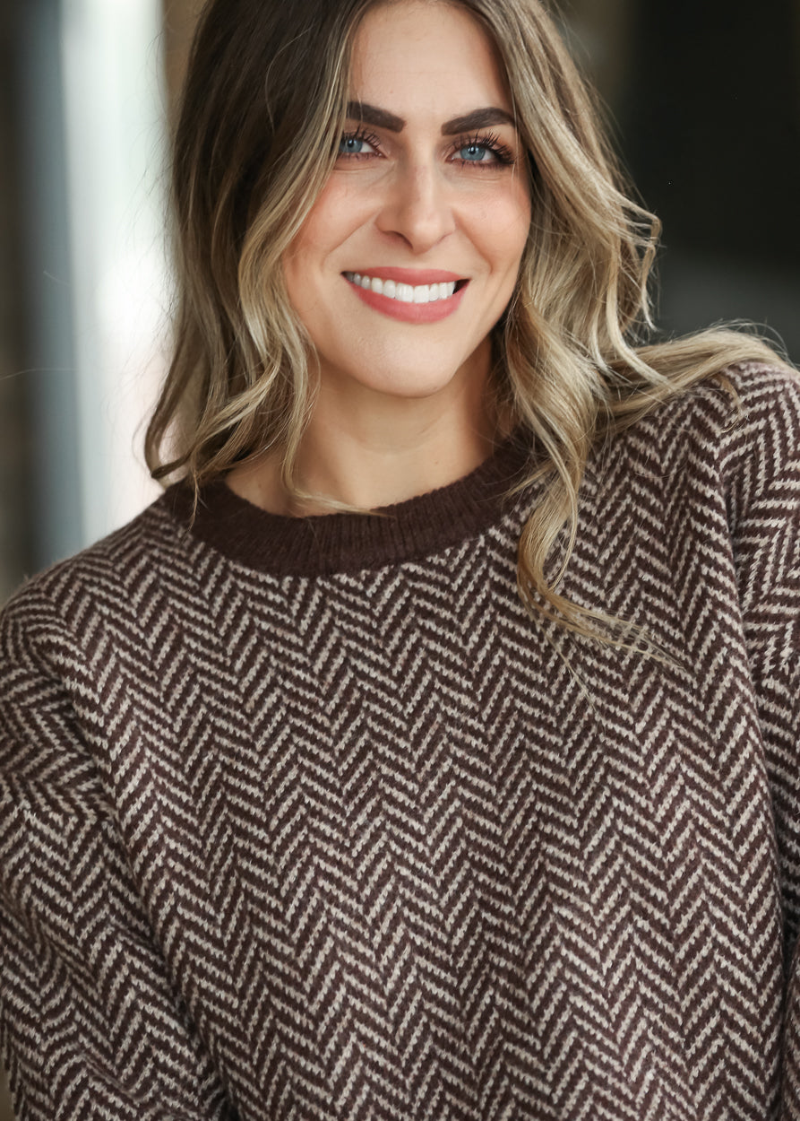 Brown taupe herringbone crewneck sweater with ribbed neckline and textured knit pattern.