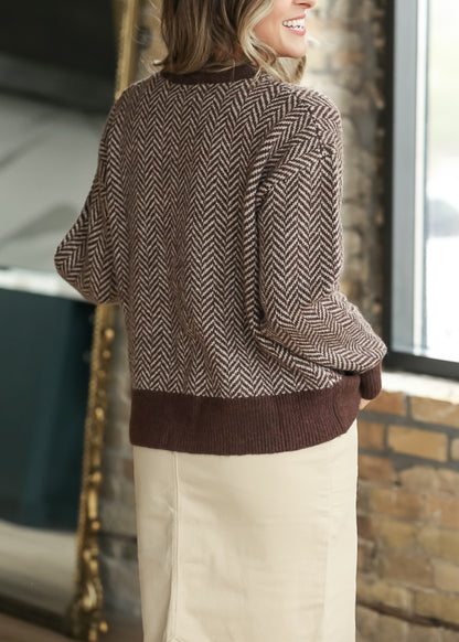Back of brown taupe herringbone sweater showing the drop shoulders, long sleeves, and ribbed hem.