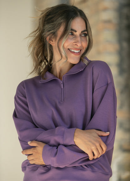 Dusty purple quarter-zip mock neck sweatshirt styled with arms crossed, showing the relaxed, loose fit.