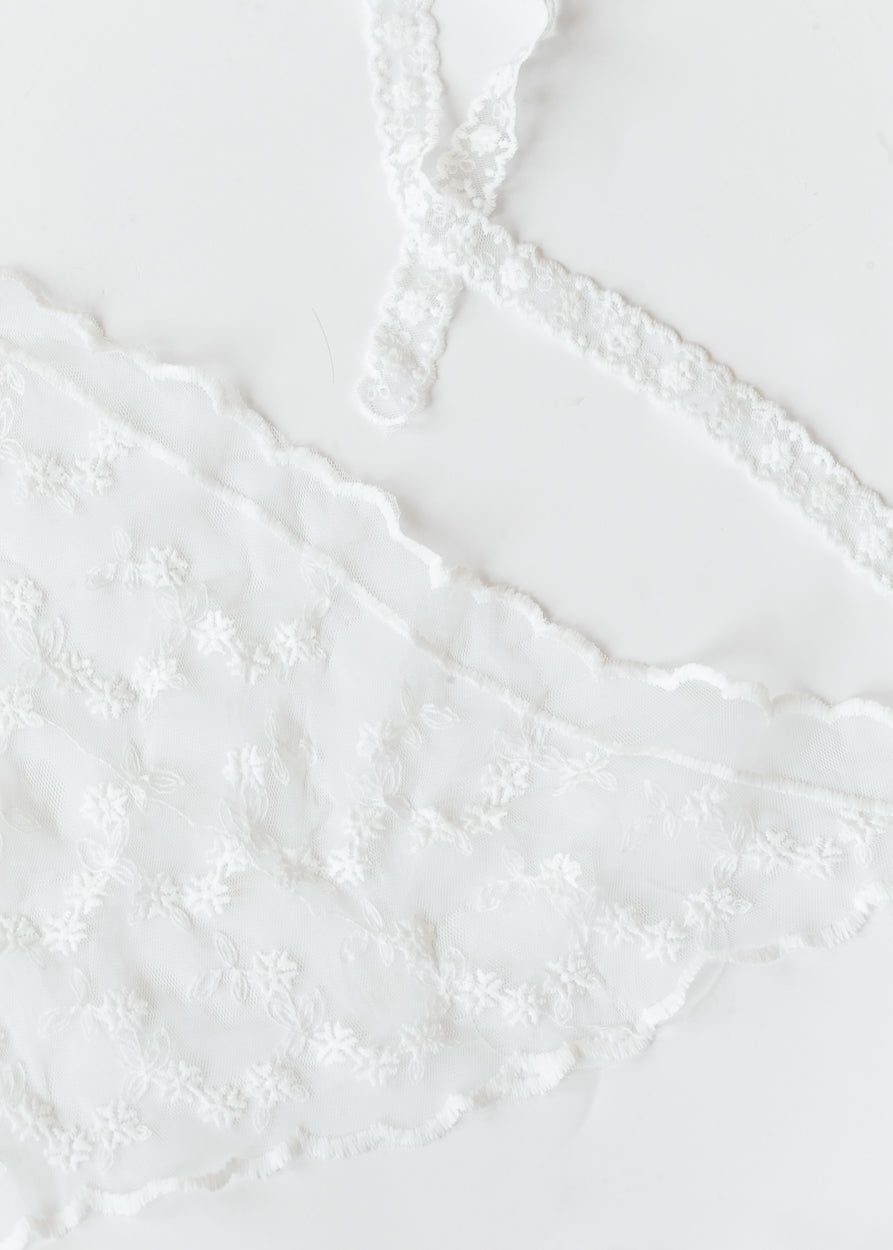 Ivory lace triangle scarf with floral embroidery, scalloped edges, and functional lace ties laid flat.