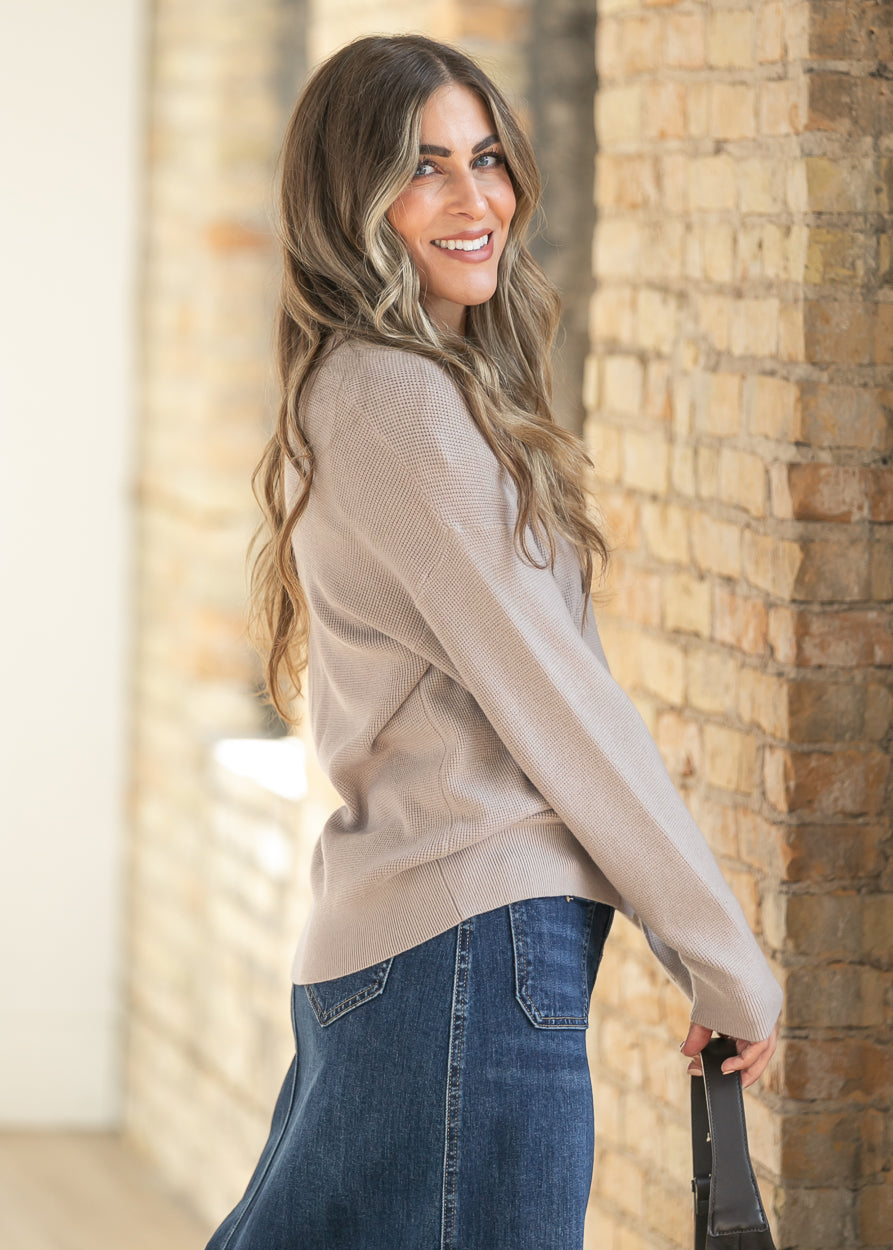 Side view of ash mocha button cardigan with V-neckline, styled with a suede crossbody bag and denim skirt.