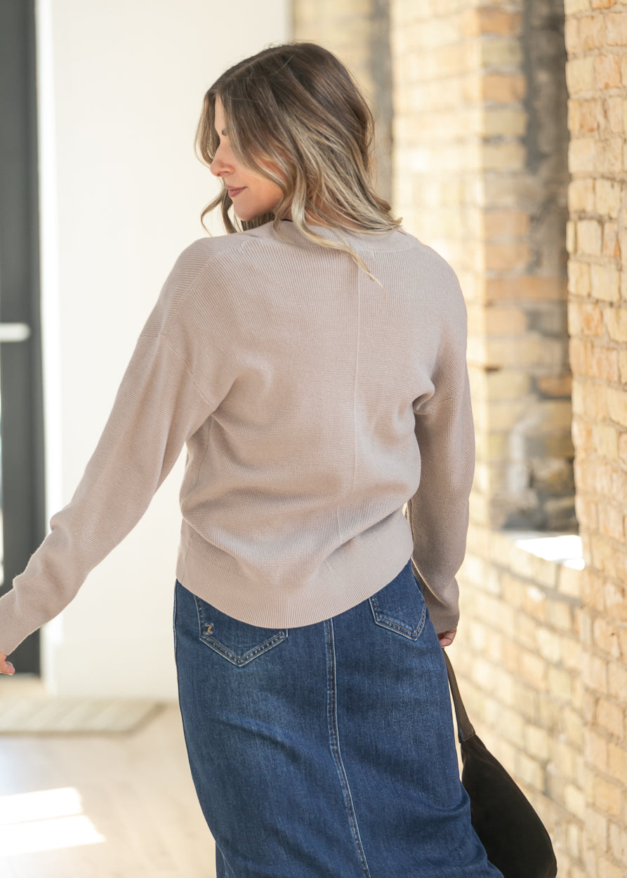 Back of ash mocha knit button cardigan, relaxed fit at the hip, styled over a dark wash denim maxi skirt.