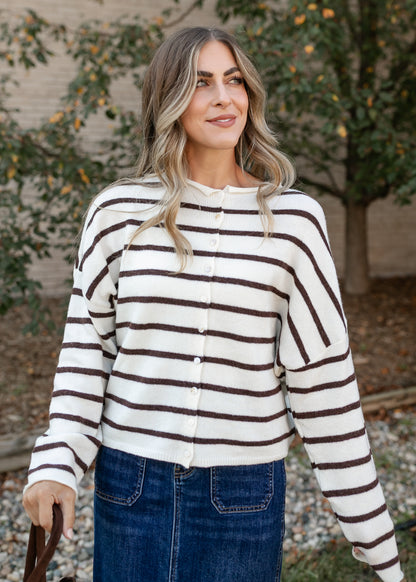 Cream and brown striped Piper cardigan with a button-front closure and drop-shoulder sleeves, styled with a denim maxi skirt.