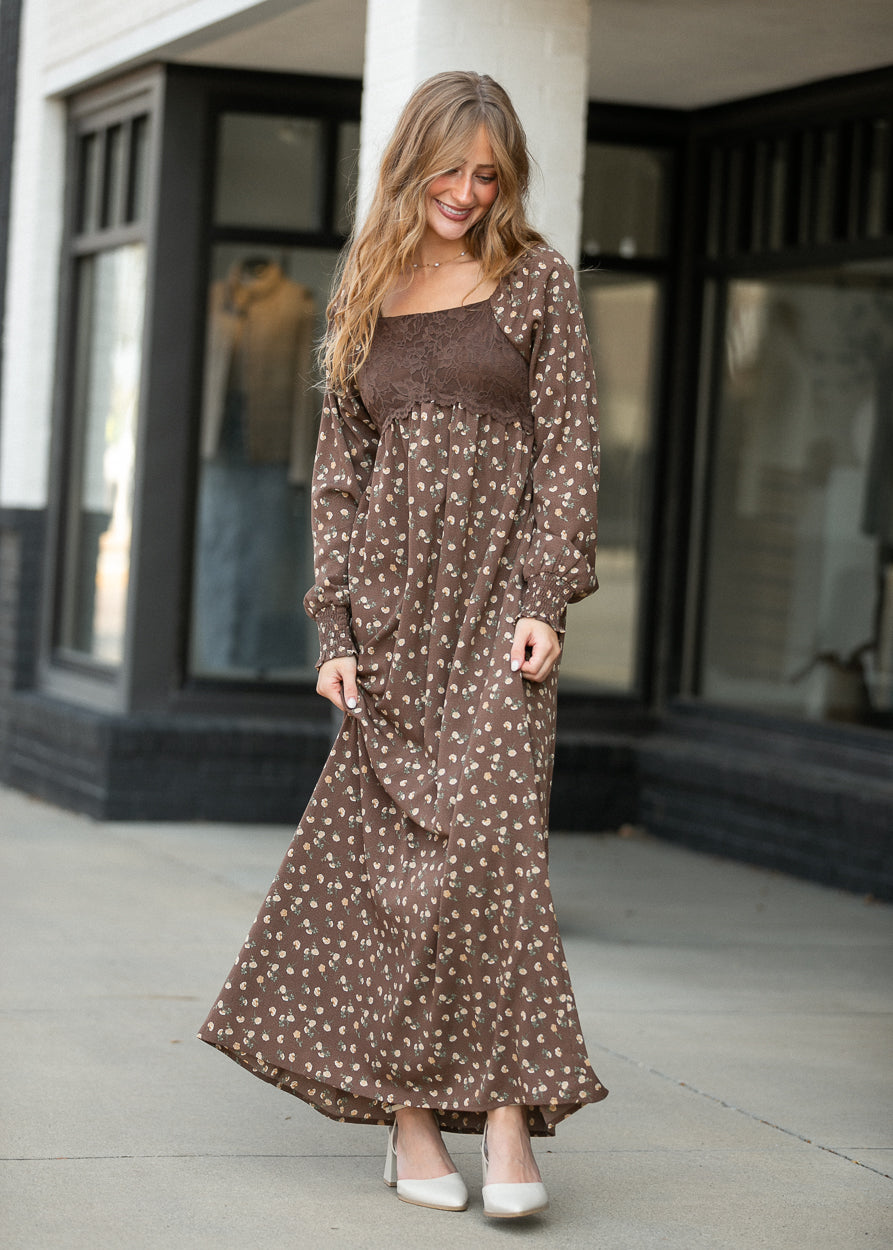 Full-length Elise brown floral maxi dress styled outdoors with cream heels and a softly gathered skirt.